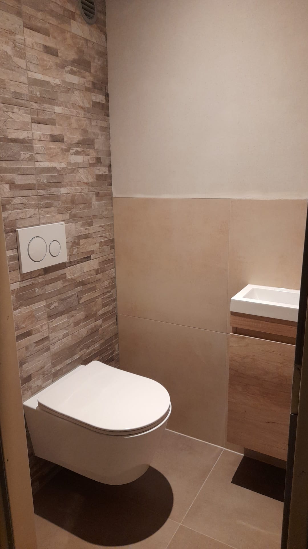 Toilet met natuursteen strips op de achterwand en hangtoilet